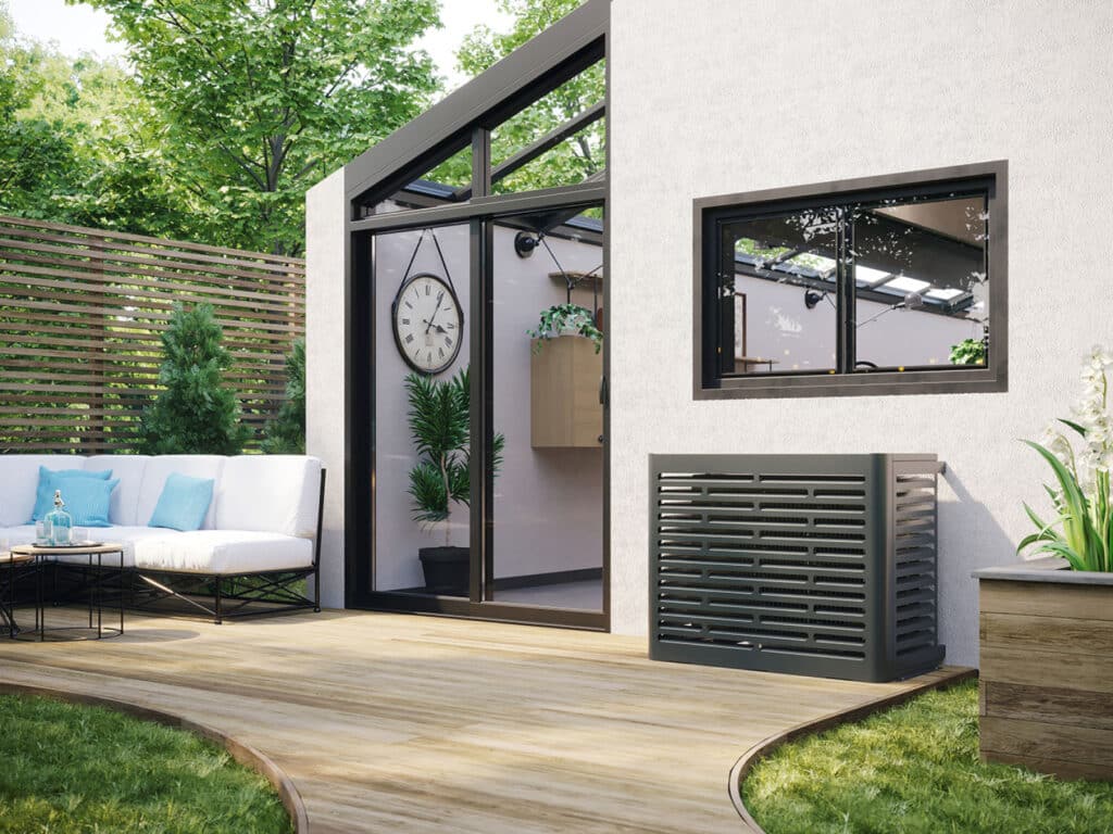 Terrasse en bois moderne avec salon de jardin blanc, véranda vitrée et cache-climatiseur gris design. Un jardin verdoyant entoure l'espace.