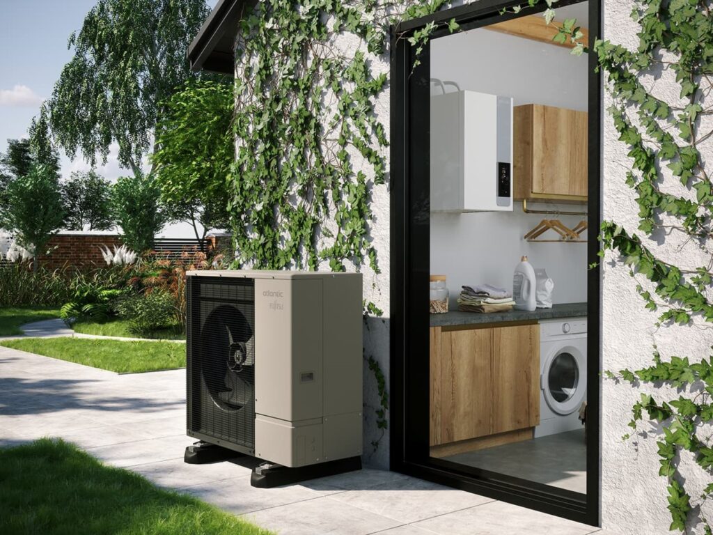 Pompe à chaleur Atlantic Fujitsu beige installée dehors. Une porte vitrée révèle une buanderie moderne avec lave-linge et chaudière murale. Jardin luxuriant.